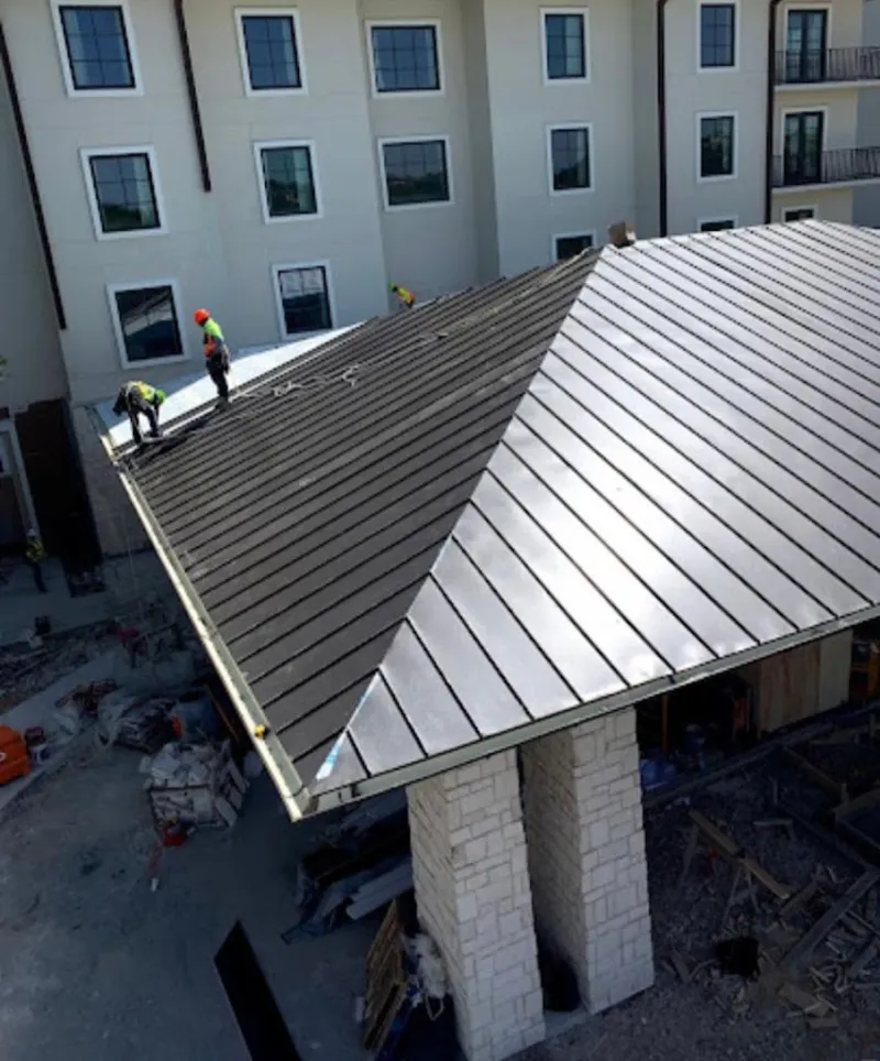 Crew installing standing seam metal roof panels on a commercial project in Oakfield